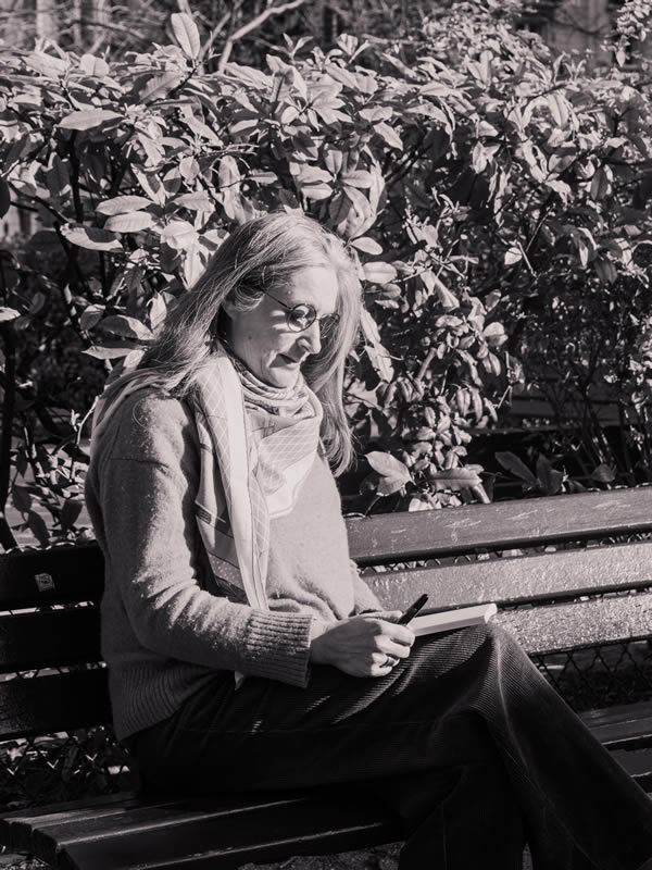 Bénédicte Nécaille, biographe, assise sur un banc en train d’écrire, reflet de son écoute et de son travail d’écriture sur-mesure.