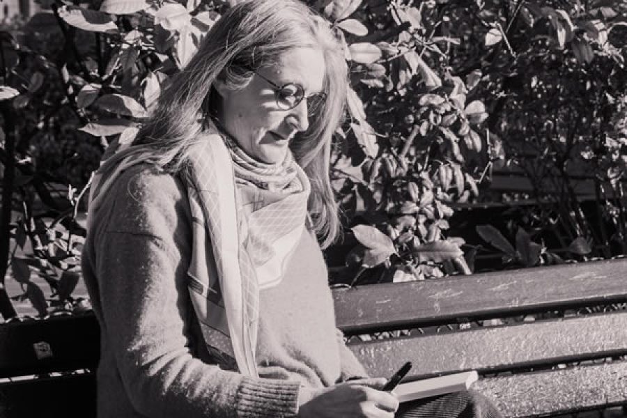 Bénédicte Nécaille, biographe, assise sur un banc en train d’écrire, reflet de son écoute et de son travail d’écriture sur-mesure.