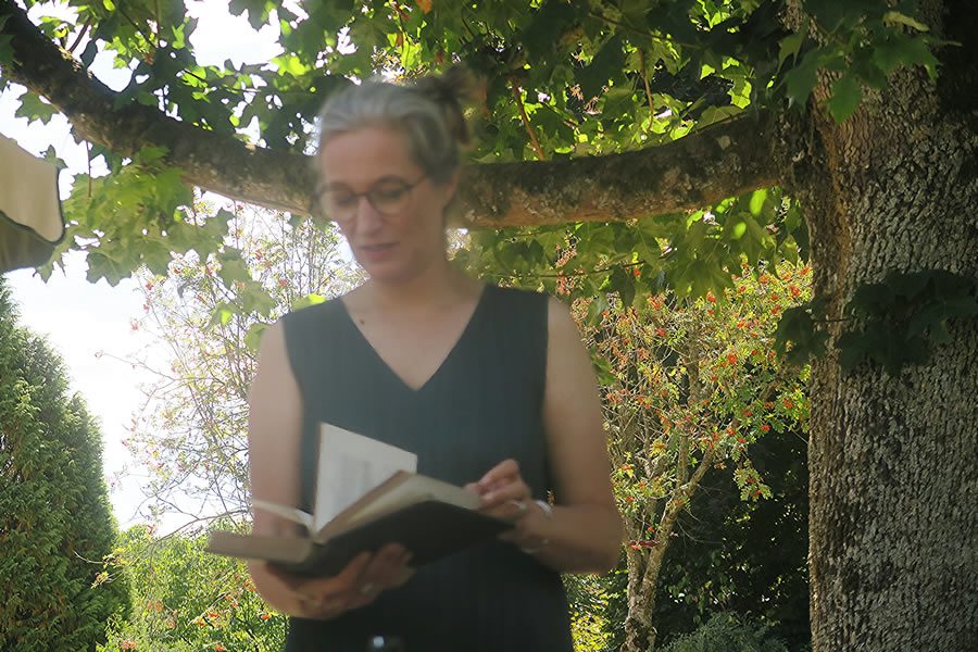 Bénédicte Nécaille, biographe, tenant un livre à la main sous un arbre, symbole de transmission d’histoires de vie.